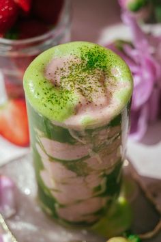 a green drink with strawberries in the background