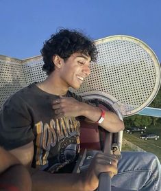 a young man sitting in the driver's seat of a car with his hand on the steering wheel