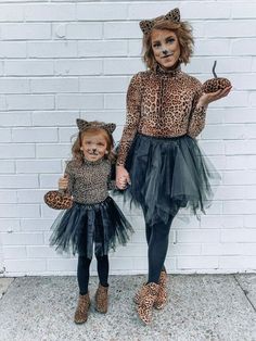 two children dressed up in animal print and black tulle skirts, one holding the hand of another child's hand