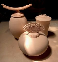 three white vases sitting on top of a table