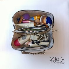 a purse filled with lots of different types of hair and beauty products on top of a white surface