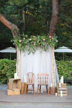 two wooden chairs sitting next to each other in front of a white drape covered wall