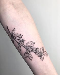 a branch with leaves and berries tattoo on the right arm, it is black and white