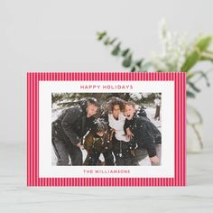 a holiday card with an image of three people in the snow and flowers behind it