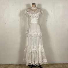 a white dress on a mannequin stand in front of a wall and tile floor