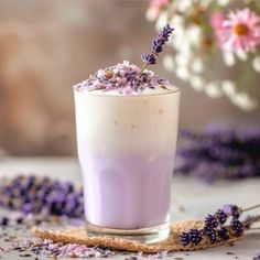 a glass filled with purple liquid and lavender sprinkles on top of it