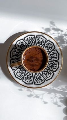 a cup of coffee sitting on top of a saucer next to a shadow cast wall