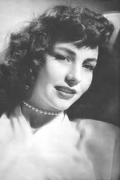 an old black and white photo of a woman wearing pearls on her neck, smiling at the camera