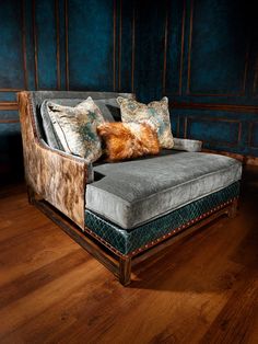 a gray couch with pillows on it in a blue walled living room, next to wood flooring