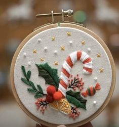 a hand embroidered christmas decoration with candy canes and holly