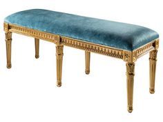 a gold bench with blue upholstered cushion on it's sides and legs