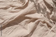 the shadow of a person's hand on an unmade bed sheet that has been washed