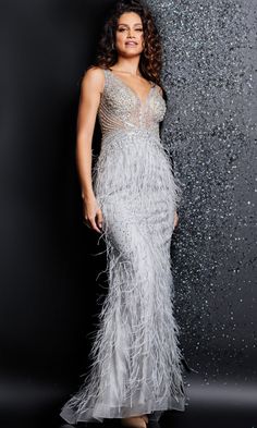 a woman in a silver dress standing next to a black wall with glitter on it