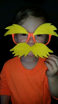 a young boy wearing sunglasses and a fake mustache with yellow felt wings on his face