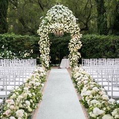 an outdoor wedding ceremony with white flowers and greenery