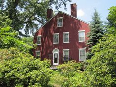 a red house surrounded by trees and bushes