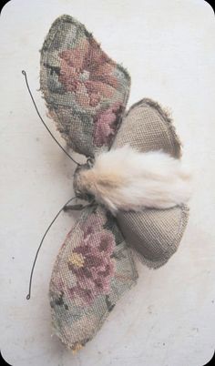 two pieces of fabric with flowers and feathers attached to each other on a white surface