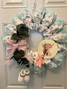 a wreath made out of diapers and baby booties hangs on the front door