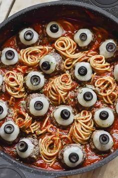 a pan filled with pasta covered in googly eyes and black olives on top