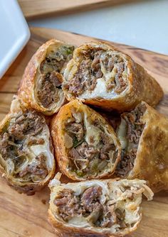 a wooden cutting board topped with meat and cheese roll cut in half on top of a white plate