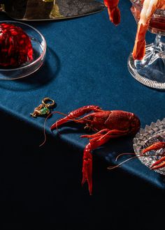 two craws on a blue table cloth next to some wine glasses and food