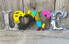 the word love spelled out in colorful letters on a wooden surface with bats and spider webs