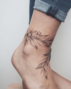 a woman's foot with a flower tattoo on the side of her leg and ankle