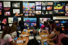 a group of people sitting around a table in front of pictures on the wall behind them