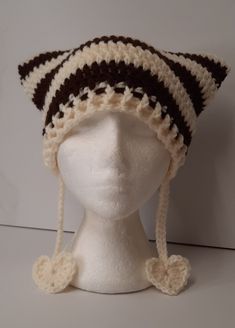 a white mannequin head wearing a crocheted hat with brown and white stripes