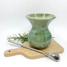 a green vase sitting on top of a wooden cutting board