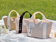 three bags sitting on top of a white blanket next to flowers and an orange juice