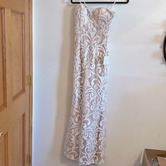 a white dress hanging on a hanger next to a door with a clock in the background