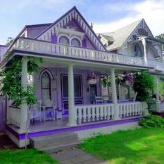 a large white house with purple trim on the front porch