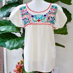 "The Yucatan embroidered top is beautifully made in Merida Yucatan, Mexico, each piece is  fully hand embroidery. Details: Size S/M - measurements: Bust: 40\" - 27.5\" length(shoulder to bottom Hem) - Cotton  thread Embroidered - Material: 100% Cotton - split sides - All items are shipped from the US All Mi Mundo Mexicano  items are 100% handmade by artisans in Mexico. Each stitch and item is completely unique and one-of-a-kind, so you'll never find two that are exactly the same! All  items may vary slightly in size, color, and design - that's what makes handmade items so special and charming!  Your Purchase supports artisans craft and families ." White Tops With Resham Embroidery For Festivals, White Resham Embroidery Top For Festivals, Bohemian Embroidered Top With Floral Design For Festive Occasions, Bohemian Embroidered Top For Festive Occasion, Bohemian Floral Embroidered Top For Festive Occasions, Festive Short Sleeve Top With Embroidered Neckline, Traditional Spring Peasant Top With Embroidered Neckline, Festive Tops With Intricate Embroidery And Short Sleeves, White Floral Embroidered Top For Festivals