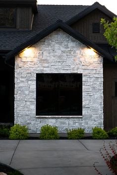 a white brick house with two windows and lights on the side of it's face