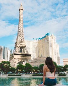 a woman sitting in front of the eiffel tower looking out over the water