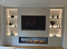 a modern living room with built in shelves and a flat screen tv mounted on the wall