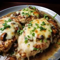 a white plate topped with chicken covered in gravy and green garnish