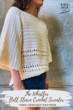 a woman standing in front of a wall wearing a white crochet sweater and denim shorts