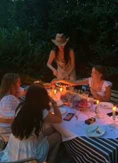 a group of women sitting around a table with candles on it