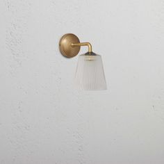 a light that is on the side of a wall with a glass shade hanging from it