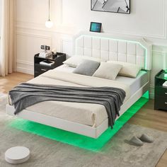 a white bed sitting on top of a wooden floor next to a green light under it