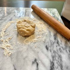 a doughnut on a marble counter next to a rolling pin