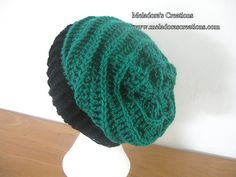 a green and black knitted hat sitting on top of a white mannequin head