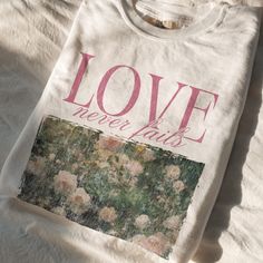 a t - shirt with the words love never ends on it sitting on a bed