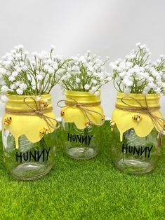 three mason jars with flowers in them sitting on the grass, labeled'hummy '