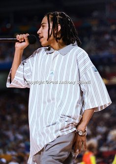 a man with dreadlocks on his head singing into a microphone at a sporting event