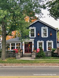 a blue house with white trim and red chairs on the front porch is decorated for halloween