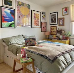 a bed sitting in a bedroom next to a window with pictures on the wall above it