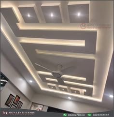 the ceiling is decorated with white lights and square designs on it, as well as a fan